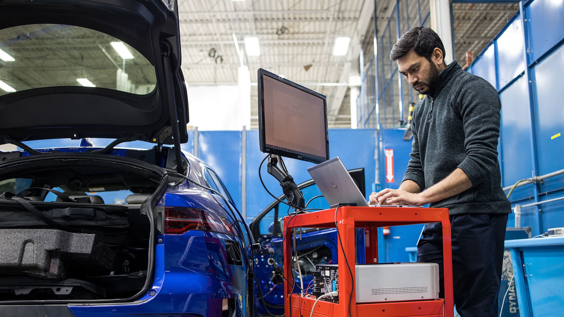 Multimatic Electronic Systems - Man working on a computer by a vehicle